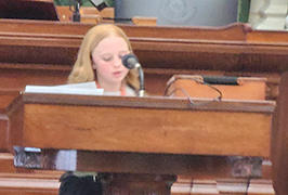  A girl stands behind a podium.